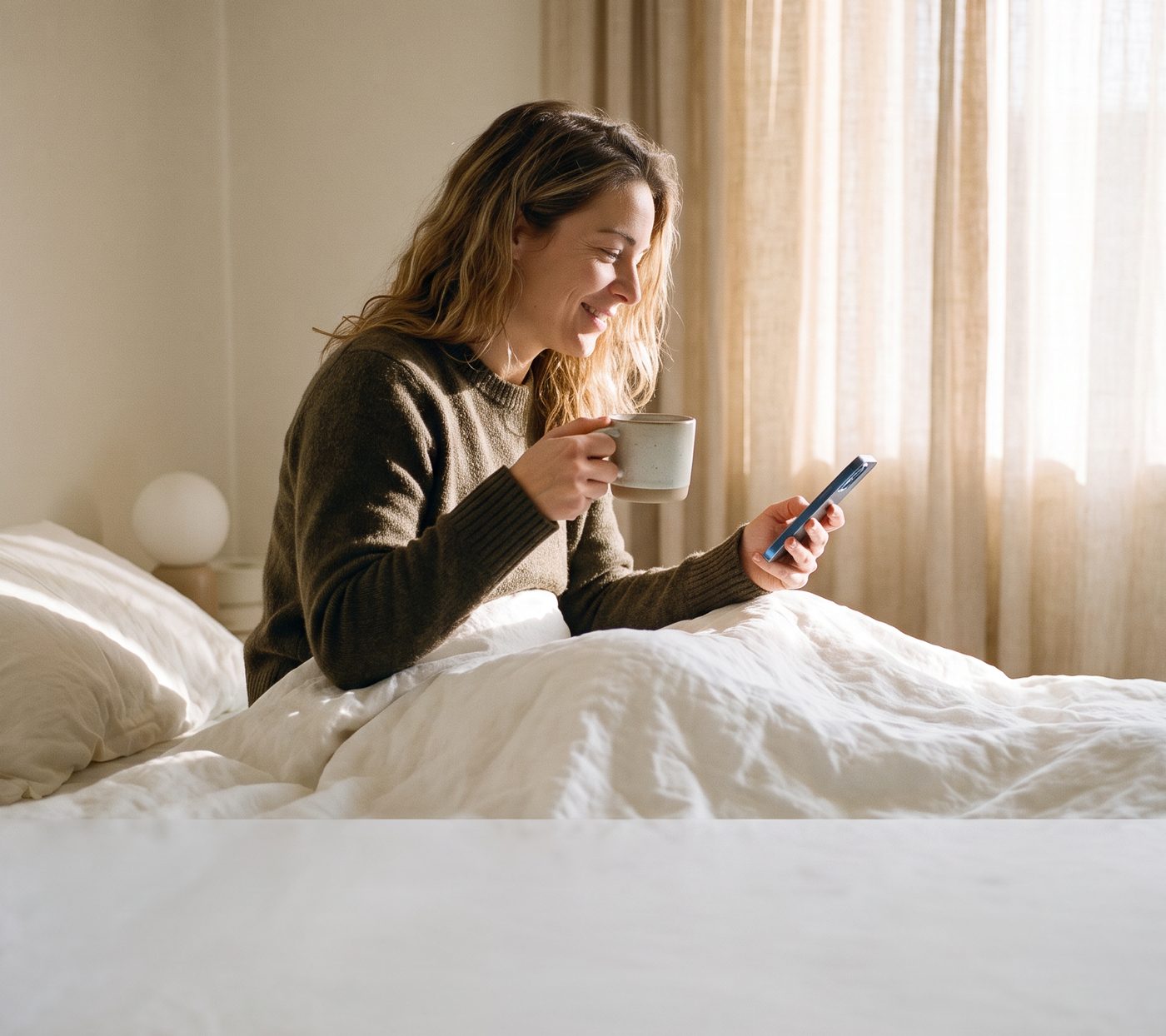 The same woman three days later, sitting up in bed in morning light with coffee and her phone